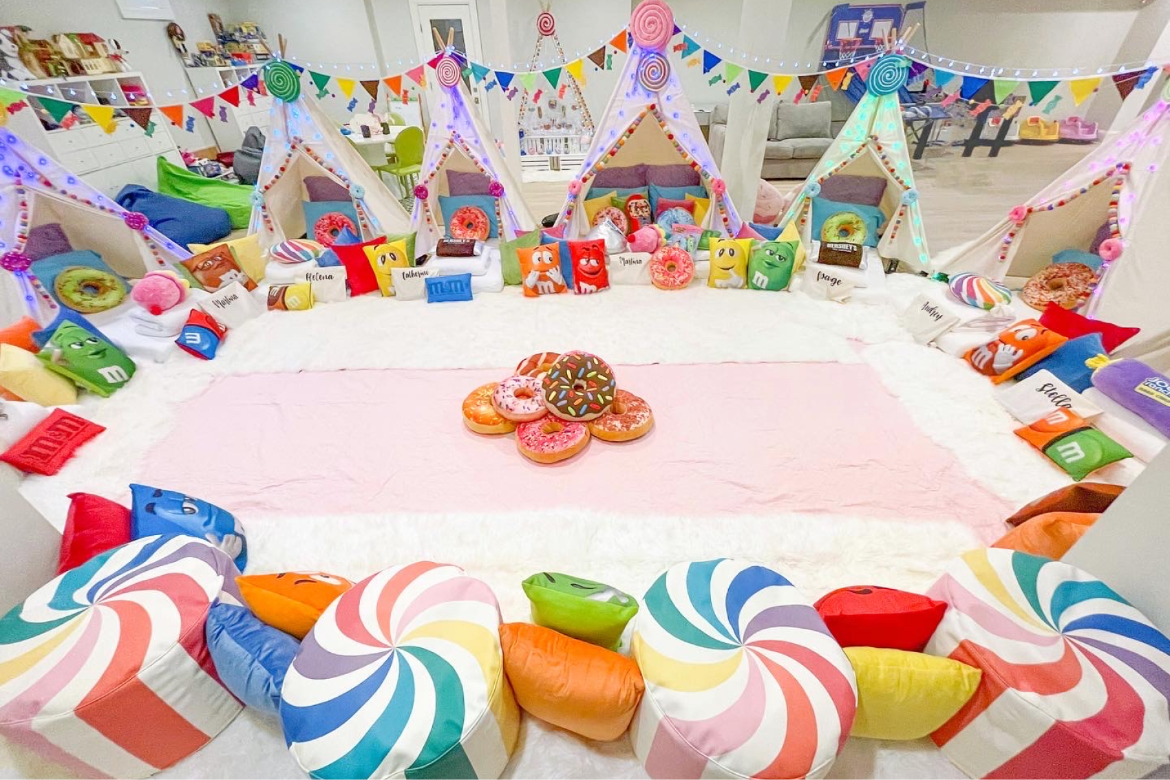 A semi-circle of cots inside of teepees with candy and donut pillows.