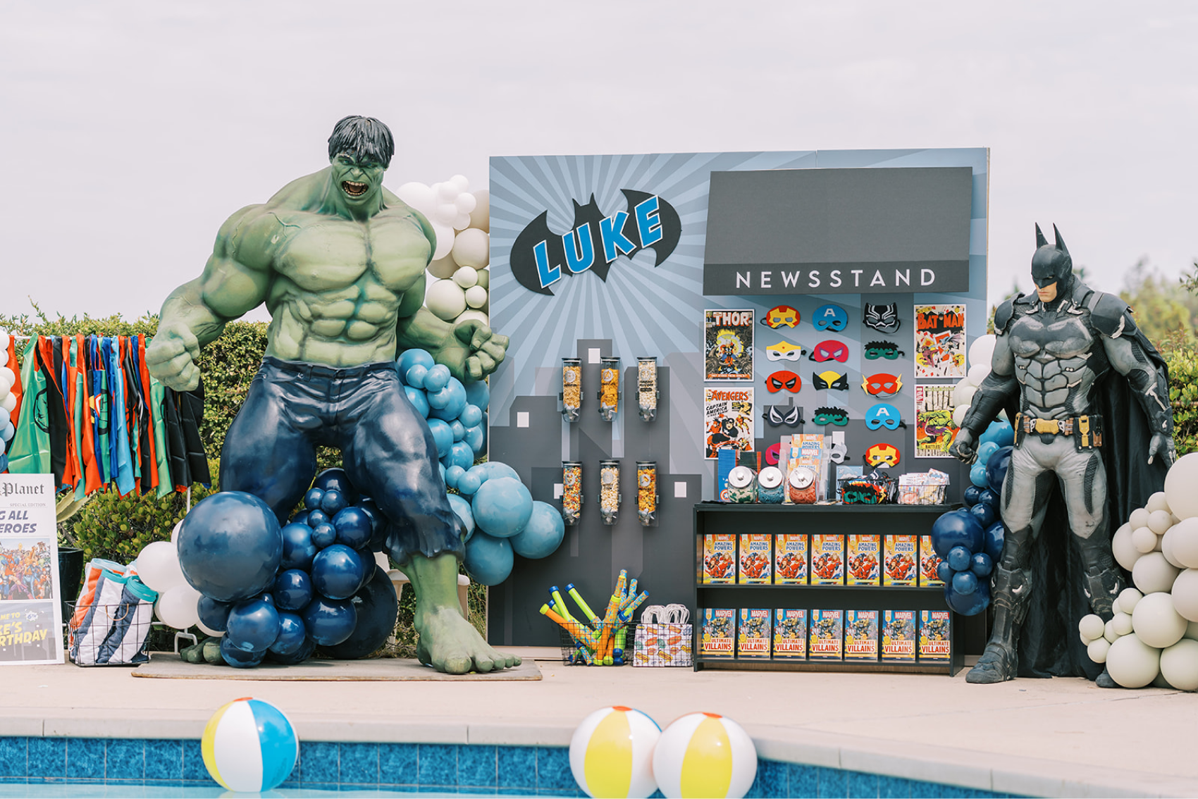 Superhero-themed party decor featuring giant Hulk and Batman sculptures.