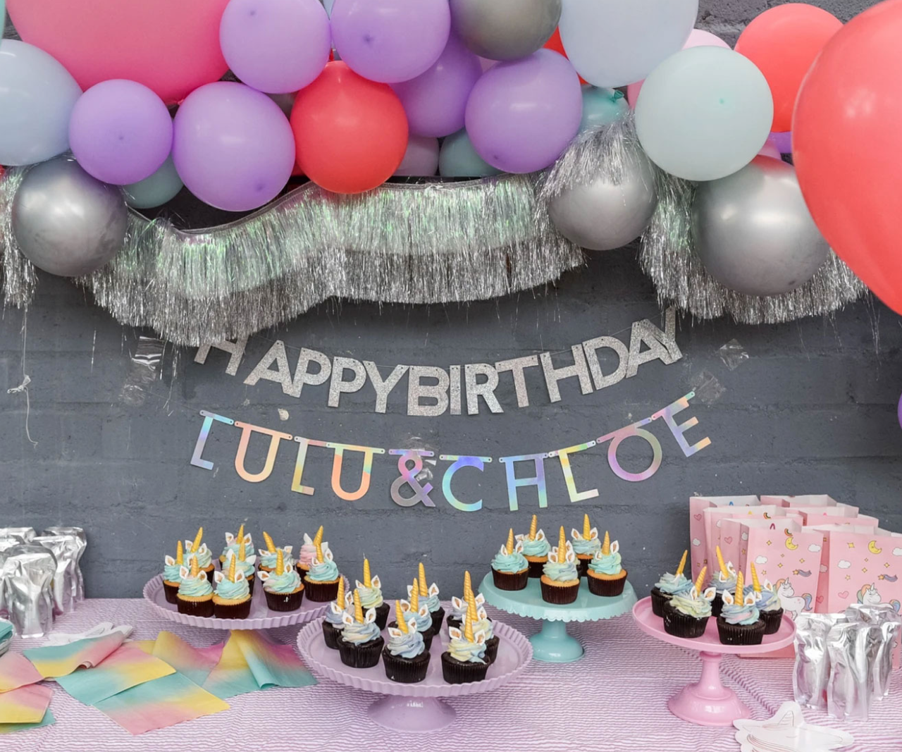 A table with cupcakes, goodie bags and balloons.