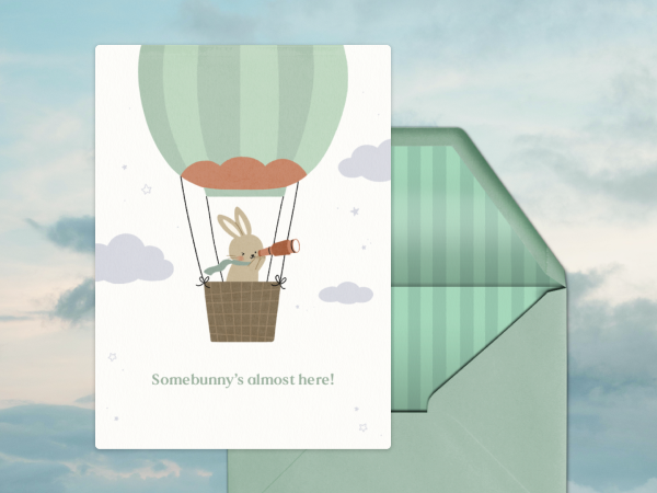 A baby shower card with a bunny in a hot air balloon on it.