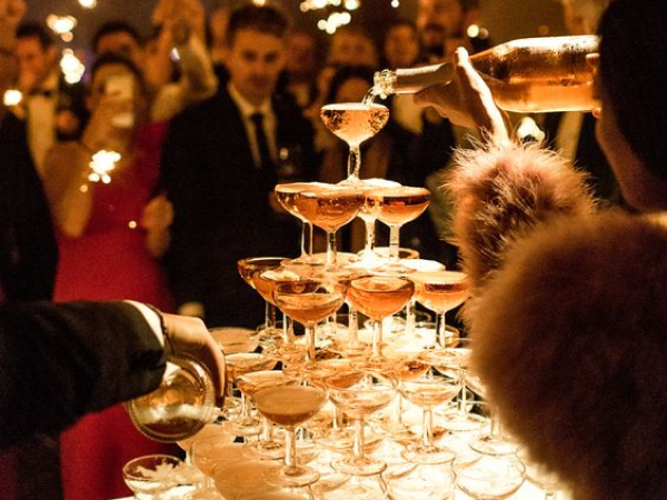 Champagne tower surrounded by people.