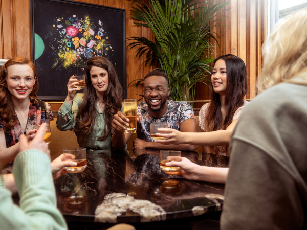 People seated around a table, smiling and raising their glasses for a toast.